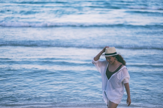 Une femme se promenant sur la plage avec la mer et le fond de ciel bleu