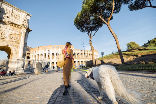 Une femme se promène avec un chien près du colisée à rome