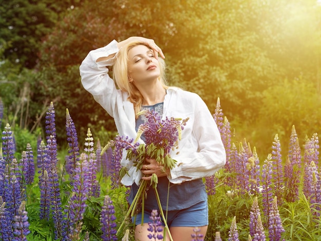 Femme se promène dans le jardin plein de lupins