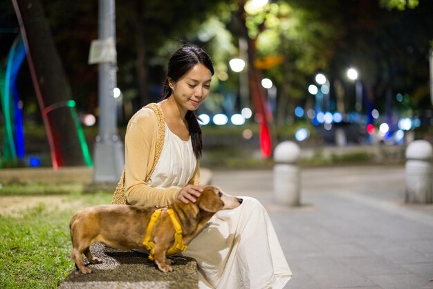 Une femme se promène avec son chien la nuit.