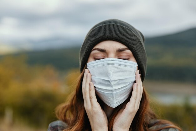 Une femme se protège du coronavirus dans un masque médical à l'extérieur dans la forêt