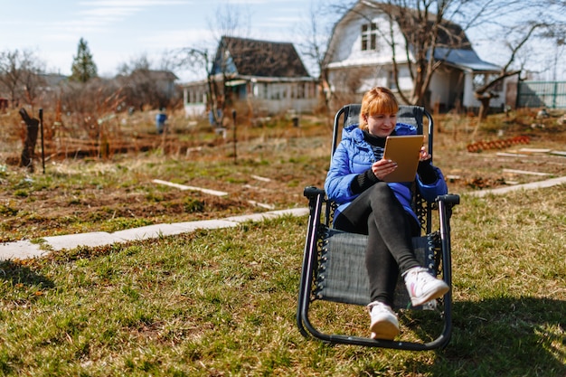 Une femme se reposant sur une chaise avec une tablette à sa datcha