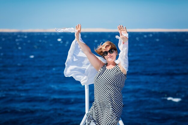 Femme se reposant sur le nez du yacht lors d'une journée d'été ensoleillée en mer et profitant des vacances et des voyages de luxe