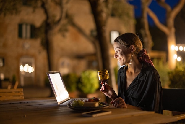 Femme se reposant avec un ordinateur portable le soir à l'extérieur