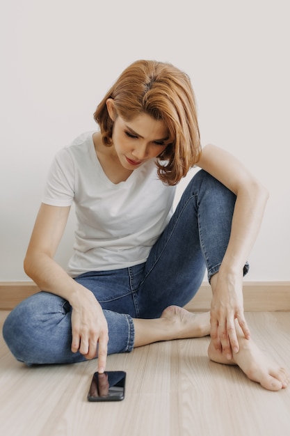 Femme se reposant et se relaxant dans la chambre avec son smartphone à la main