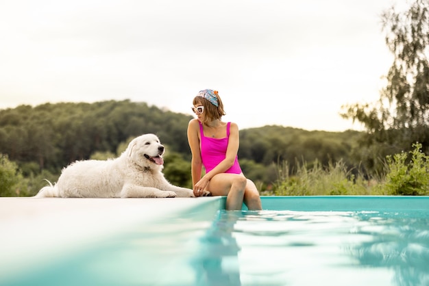 La femme se repose avec son chien mignon près de la piscine