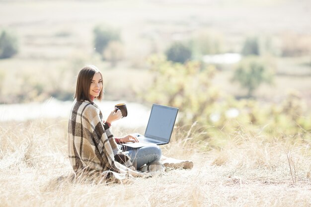 Femme se réveillant à l'extérieur. Travail à distance sur le camping. Femme tapant sur pc.