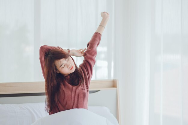 Femme se réveillant le matin en étirant ses bras. Une femme heureuse se réveille sur son lit le matin.