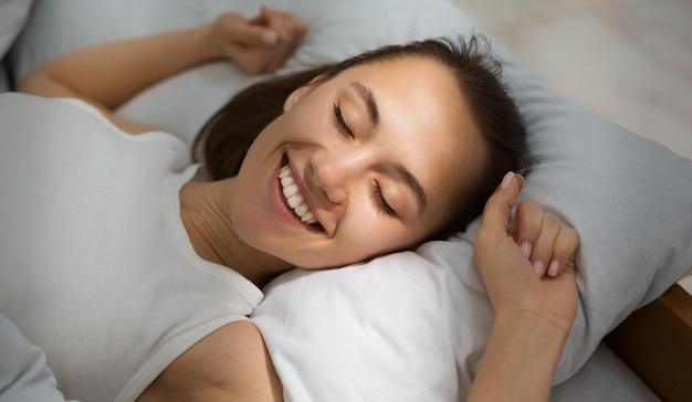 Femme se réveillant le matin qui s'étend au lit