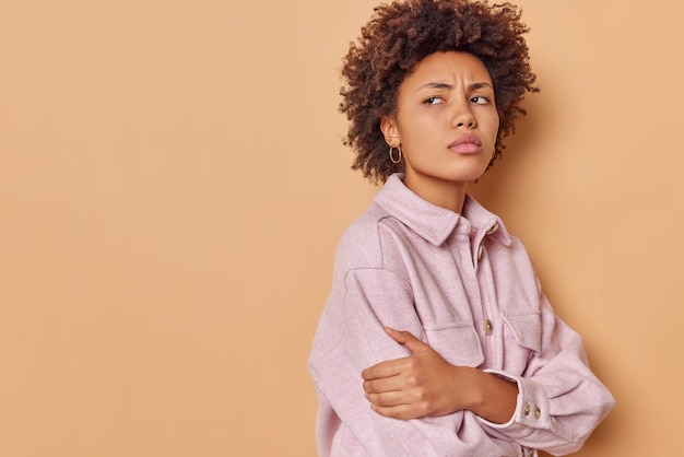 la femme se sent offensée se tient debout avec les bras croisés refuse de parler avec son petit ami se retourne vers quelqu'un habillé avec désinvolture isolé sur le beige se sent mécontent