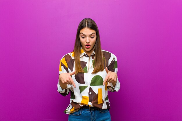 femme se sentant choquée, bouche bée et étonnée, regardant et pointant vers le bas avec incrédulité et surprise