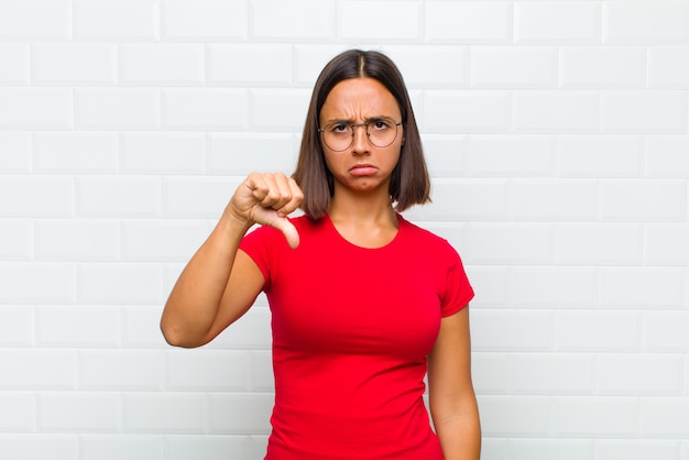 Femme se sentant en colère, en colère, ennuyée, déçue ou mécontente, montrant les pouces vers le bas avec un regard sérieux