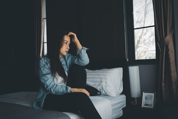 Femme se sentant seule déprimée et stressée assise la tête dans les mains dans la chambre sombre à la maison salon concept de santé mentale et émotion négative