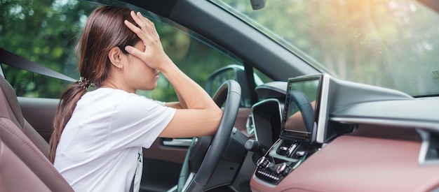 Femme se sentant stressée et en colère pendant longtemps en voiture Fille asiatique fatiguée et fatiguée ayant des maux de tête s'arrêter après avoir conduit une voiture dans un embouteillage Somnolent étirement et concept ivre