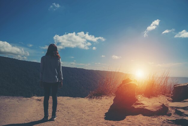 La femme se tient au ciel à la vue de montagne pour la lumière du soleil