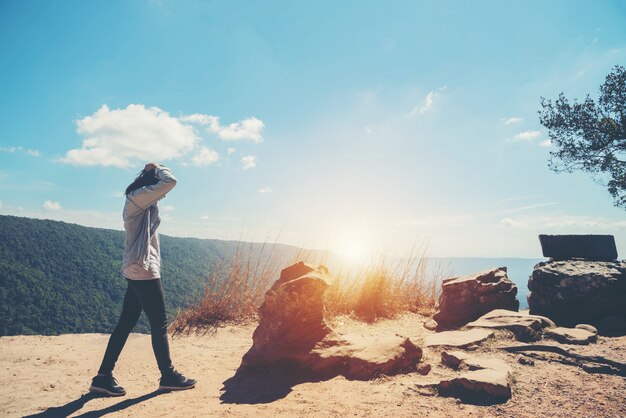 La femme se tient au ciel à la vue de montagne pour la lumière du soleil