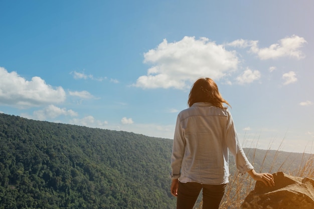 La femme se tient au ciel à la vue de montagne pour la lumière du soleil