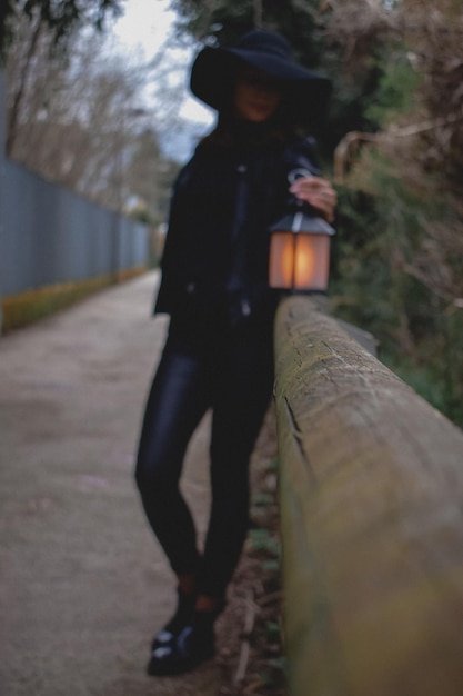 Photo une femme se tient sur un chemin avec une lanterne à la main