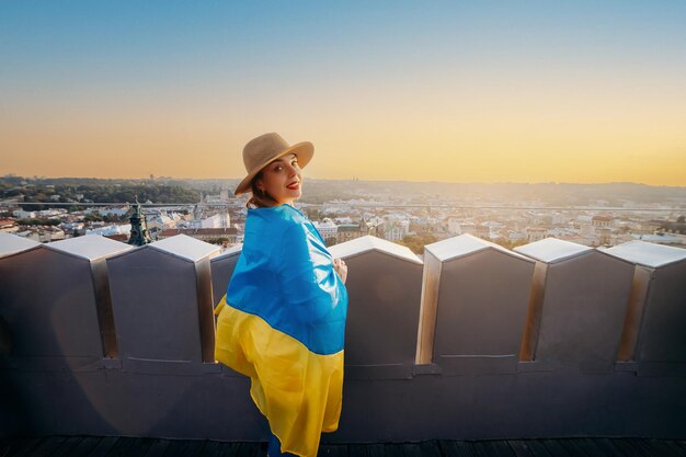 Une femme se tient debout avec le drapeau national ukrainien et l'agite en priant pour la paix au coucher du soleil à LvivxAA symbole de l'indépendance et de la force du peuple ukrainien Priez pour l'Ukraine