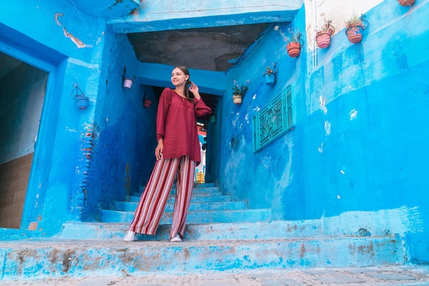 Une femme se tient devant un bâtiment bleu avec une chemise rouge qui dit "bleu" dessus.