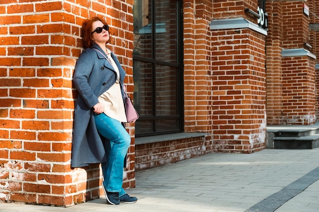 Une femme se tient devant un mur de briques avec le mot st.