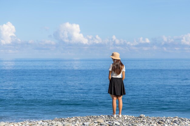 Une femme se tient devant la plage.