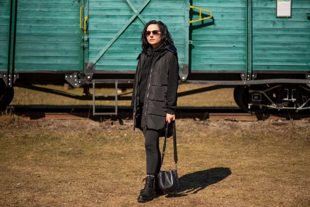 Une femme se tient devant un train vert