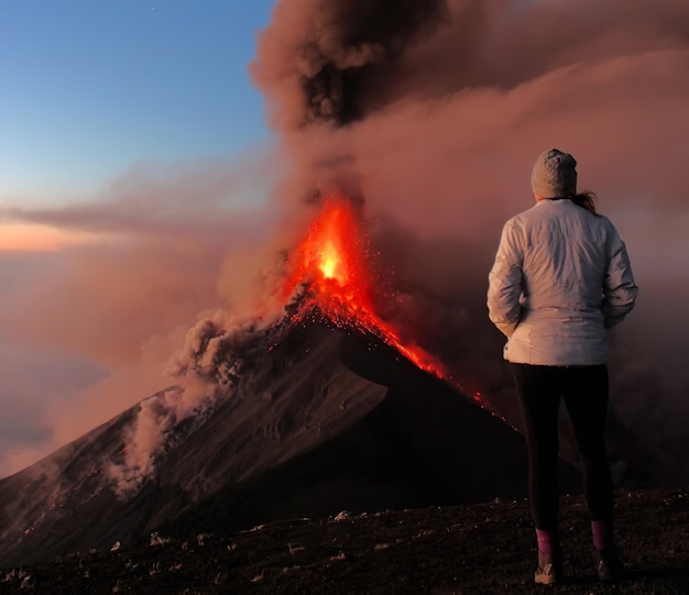 Photo une femme se tient devant un volcan couvert de fumée.