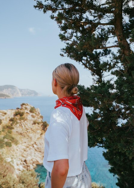 Photo une femme se tient sur une falaise face à la mer