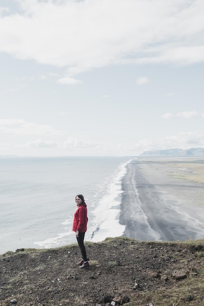 La femme se tient sur une falaise en Islande