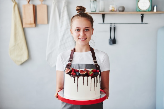 Une femme se tient à l'intérieur dans la cuisine avec une tarte maison.