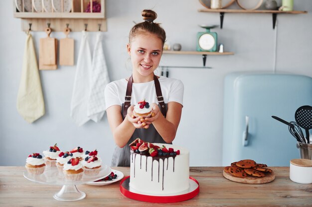 Une femme se tient à l'intérieur dans la cuisine avec une tarte maison.