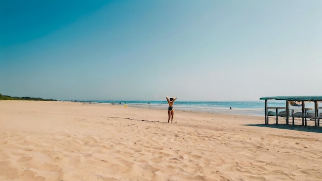 une femme se tient sur la plage avec ses bras en l'air