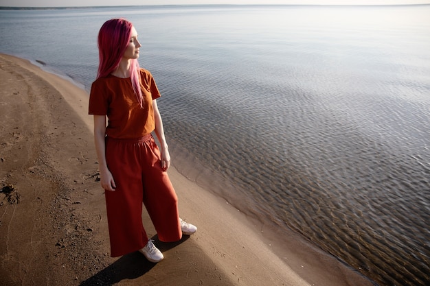 Photo une femme se tient sur le rivage et regarde la mer