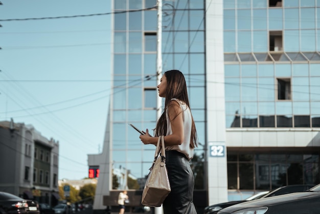 Une femme se tient sur le trottoir devant un immeuble avec un sac qui dit 22.