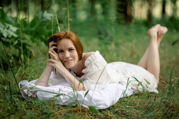 Une femme se trouve sur une clairière verte sur un oreiller dans la forêt