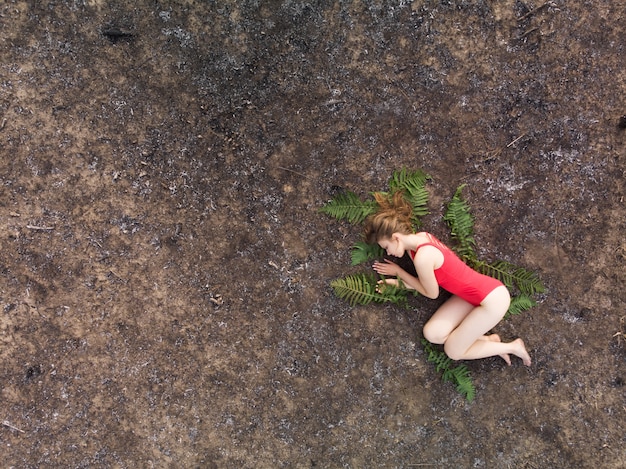 Photo une femme se trouve sur les feuilles de fougère sur le sol brûlé