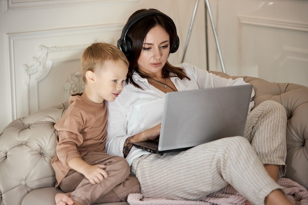 La femme se trouve à la maison sur le canapé avec des écouteurs et écoute de la musique. Journée de repos à la maison, détente et repos