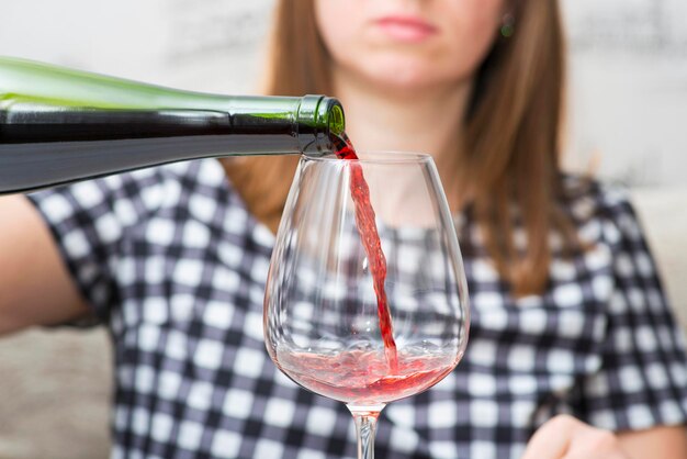 Une femme se versant un verre de vin rouge.