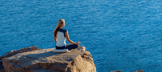 Femme, séance, lotus, position, rocher, au-dessus, mer, méditer Yoga en plein air. copyspase