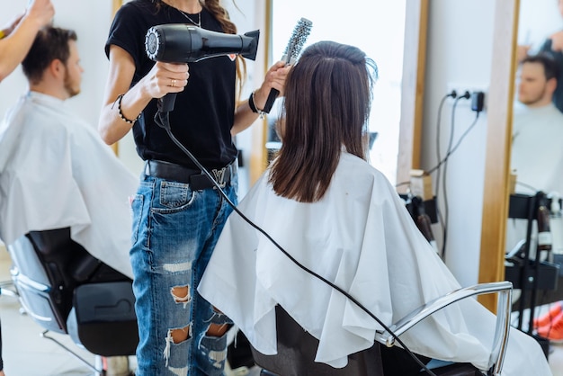 Femme séchant les cheveux dans un salon de coiffure