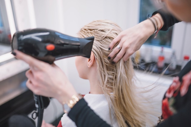 Femme séchant les cheveux mouillés du client