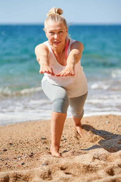 Femme séduisante âgée pendant les sports au bord de la mer.