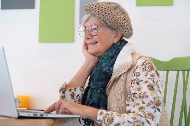 Femme séduisante caucasienne souriante assise à l'intérieur d'un café-bar à l'aide d'un ordinateur portable Dame âgée accro à la technologie dans le travail à distance