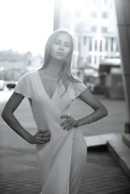 Une femme séduisante porte une tenue tendance marchant sur l'avenue sous la douce lumière du soleil du soir. Couleur monochrome