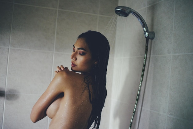 Photo une femme séduisante qui prend une douche dans la baignoire.