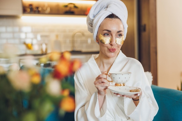 Une femme séduisante avec des soins de la peau sous les yeux qui savoure le café du matin et se détend chez elle.