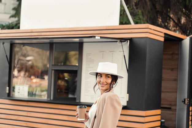 Femme séduisante souriante avec une tasse de café près du café. La femme d'affaires fait une pause.