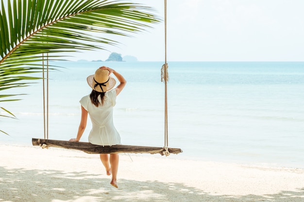 Femme séduisante voyageur assise sur une balançoire sur une plage