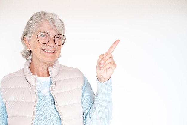 Femme senior aux cheveux blancs souriant et regardant la caméra pointant avec la main et le doigt sur le côté